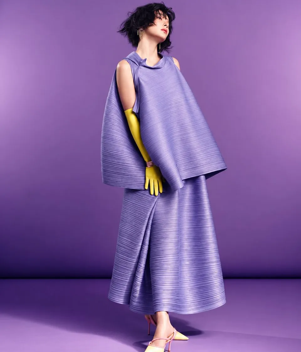 A model in a pleated purple outfit against a purple background