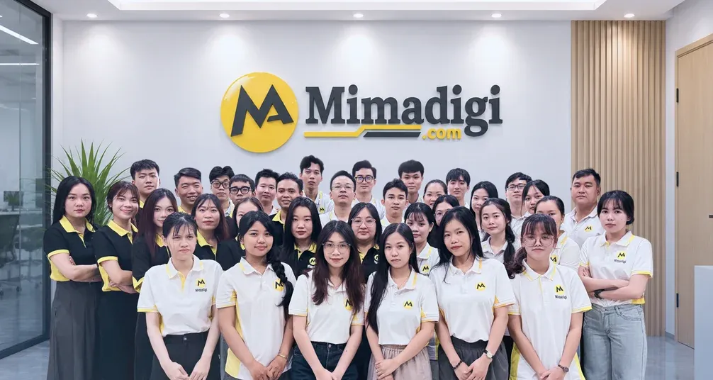 Toàn bộ nhân sự MIMA đứng thành hàng trước bảng hiệu MIMA tại văn phòng