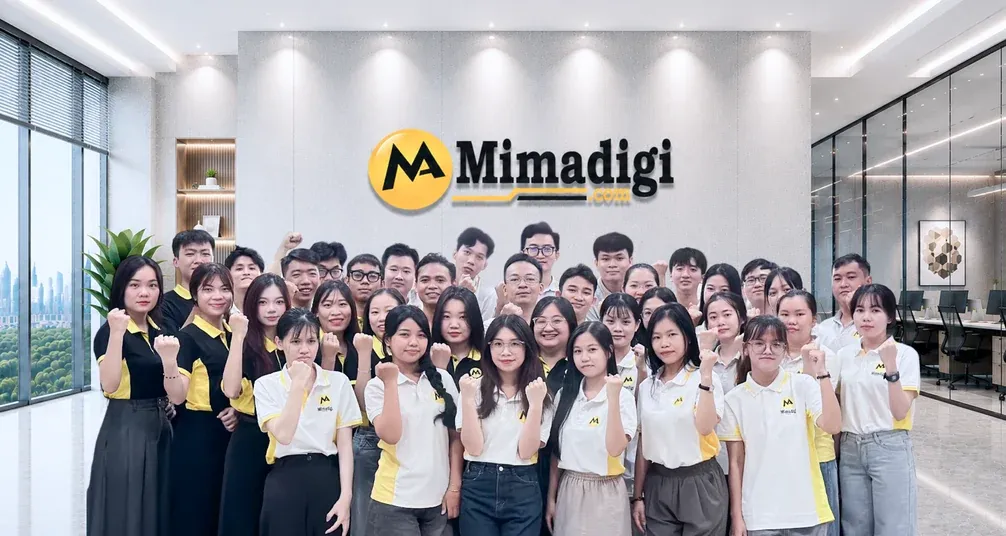Đội ngũ MIMA nắm tay tạo dáng trước bảng hiệu MIMA ở sảnh văn phòng